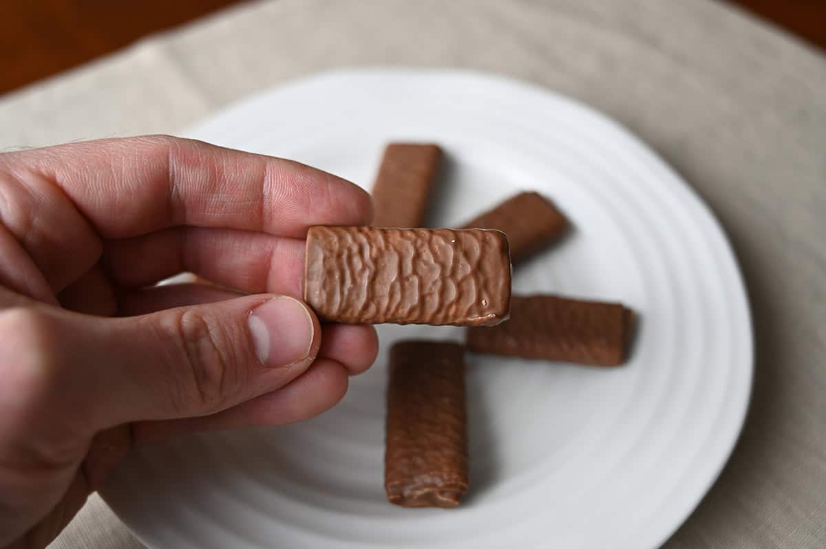 Image of a hand holding one Kirkland Signature Crepe cookie close to the camera.