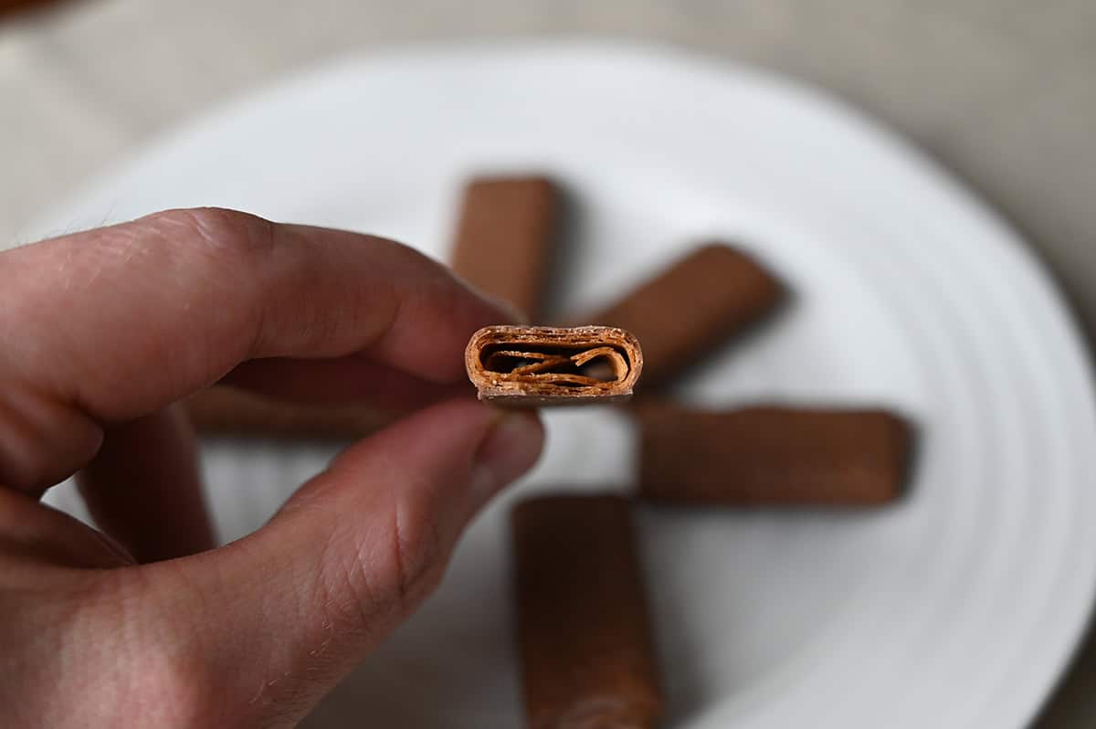 Closeup image of a hand holding one Costco Kirkland Signature Crepe with a bite taken out of it so you can see the middle. 