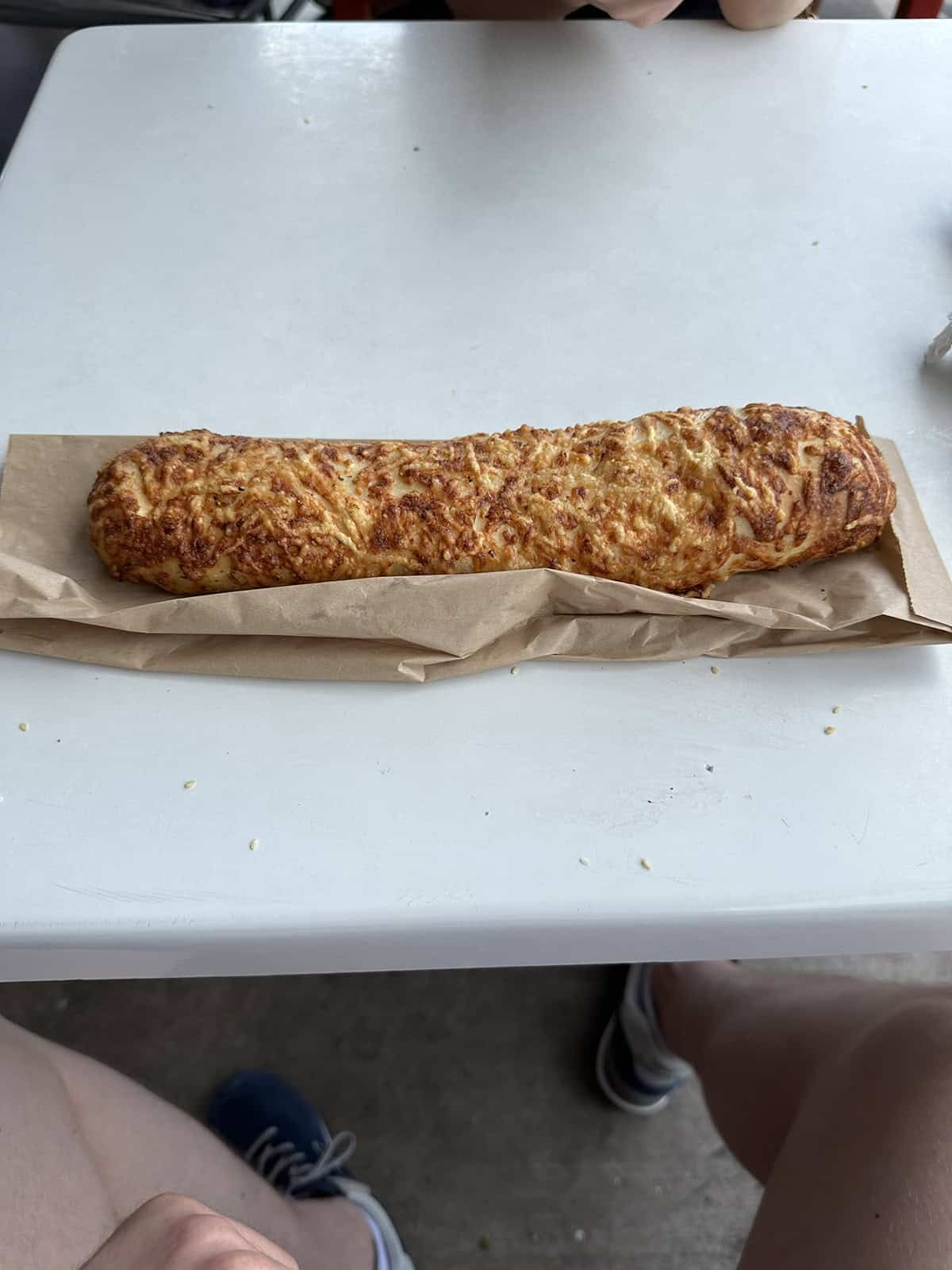 Top down image of a Costco food court chicken bake unwrapped and sitting on a paper bag that it came in.