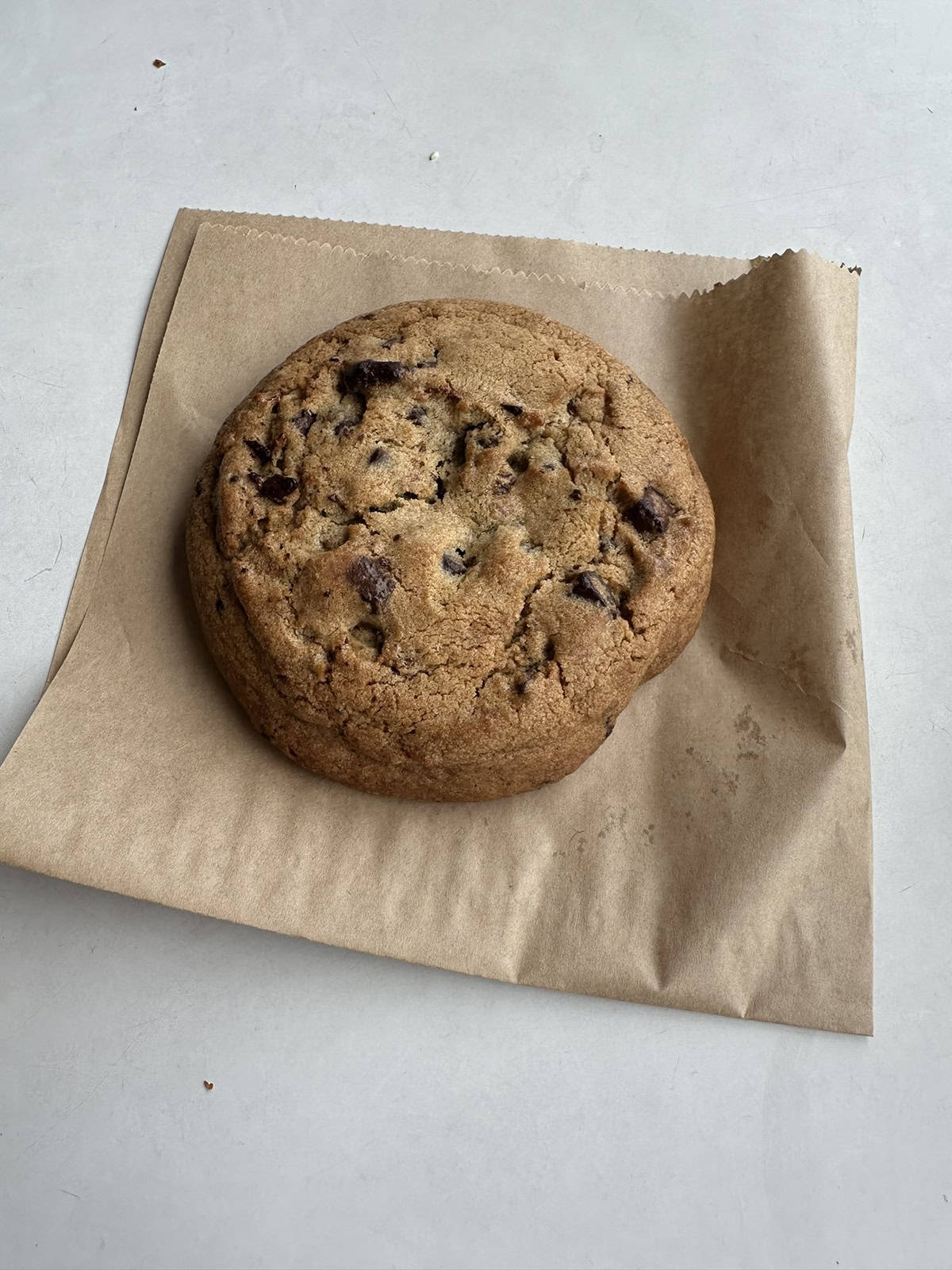 Top down image of one double chocolate chunk cookie from the Costco food court sitting on a paper bag it came in.