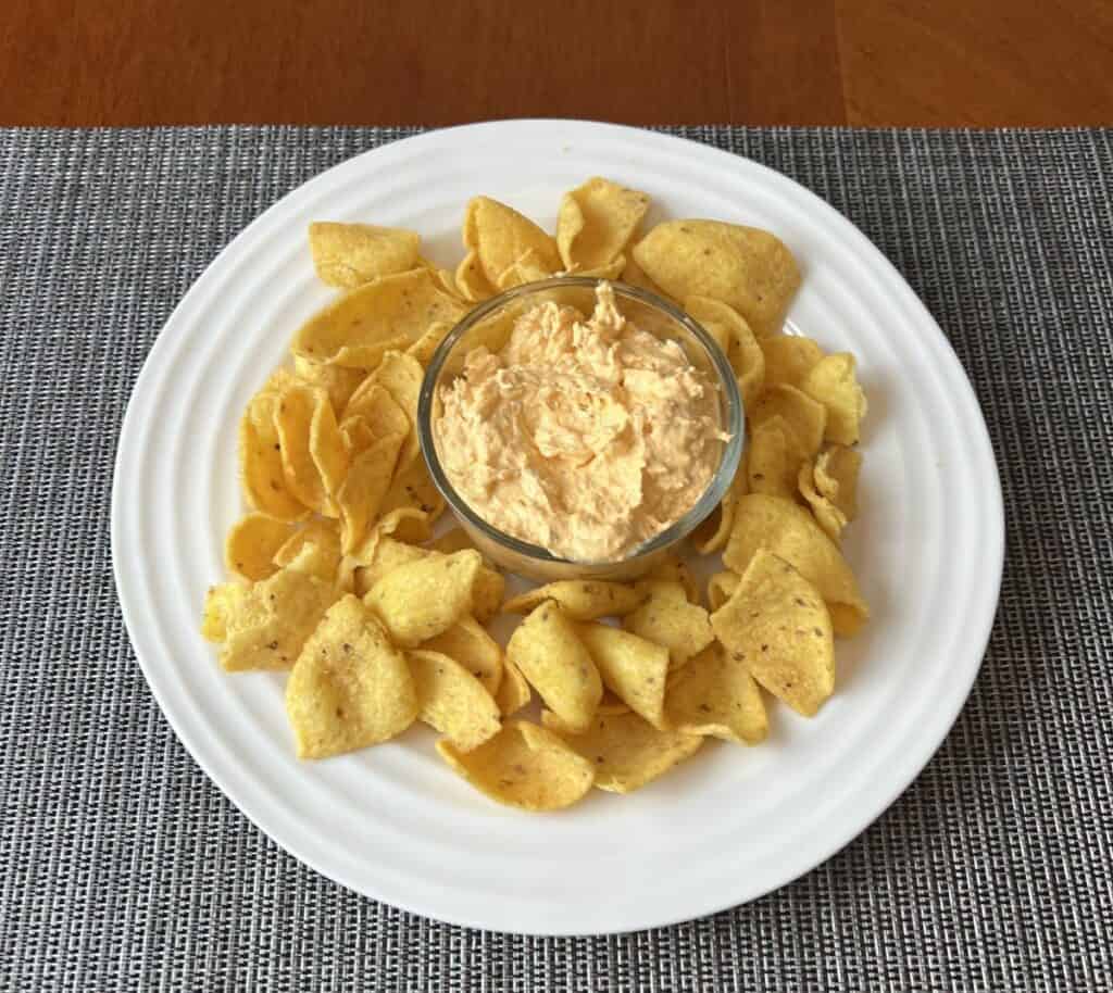 Top-down image of a plate with tortilla chips with dip in a small bowl in the middle of the plate.