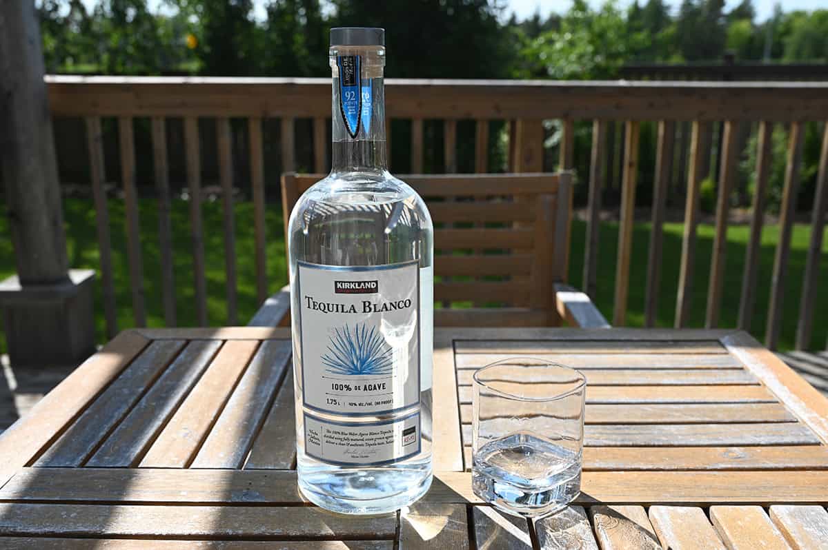 Image of the Tequila Blanco on a table outside sitting beside a glass of tequila.