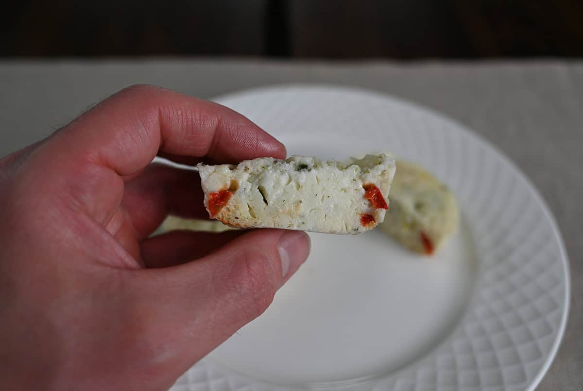 Image of a hand holding one egg white bite with a few bites taken out of it so you can see the center.