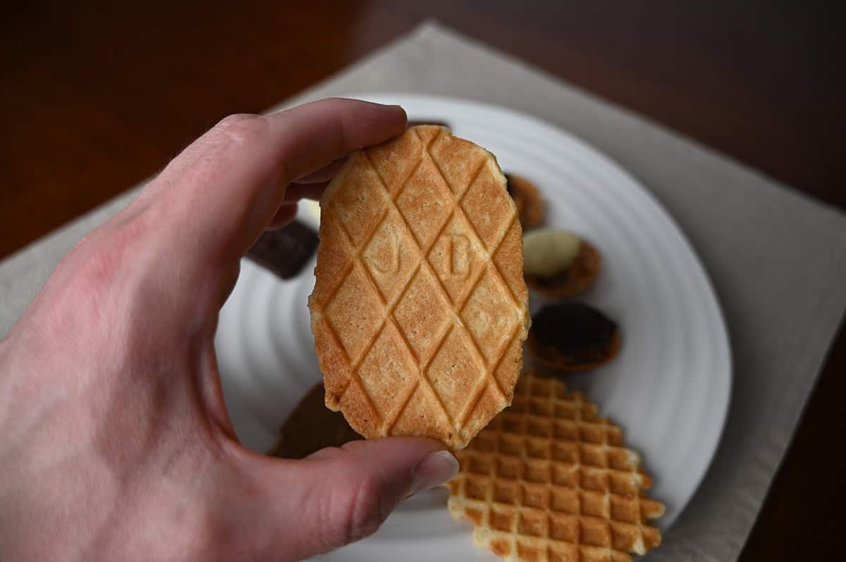 Image of a hand holding one butter biscuit close to the camera.