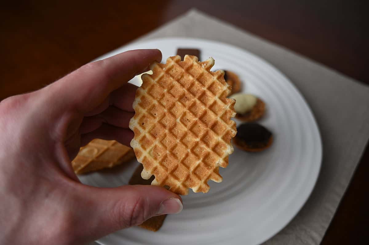 Image of a hand holding one butter waffle biscuit close to the camera.