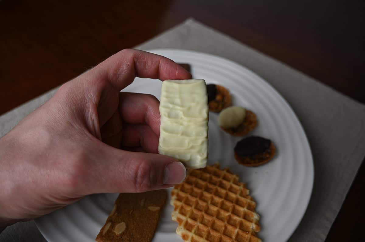 Image of a hand holding one white chocolate thin close to the camera.