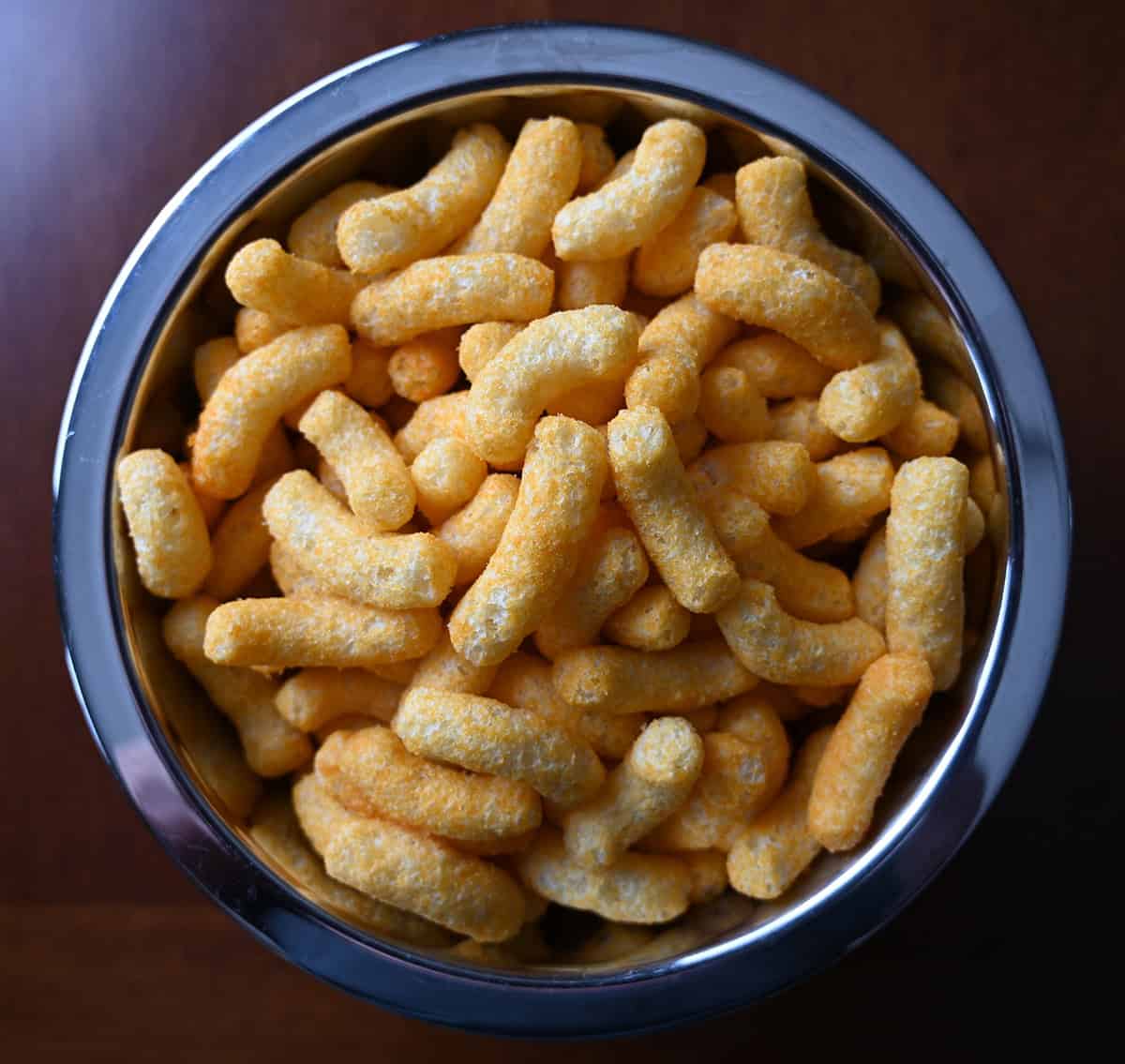 Top down image of a metal bowl with puff snacks poured into it.