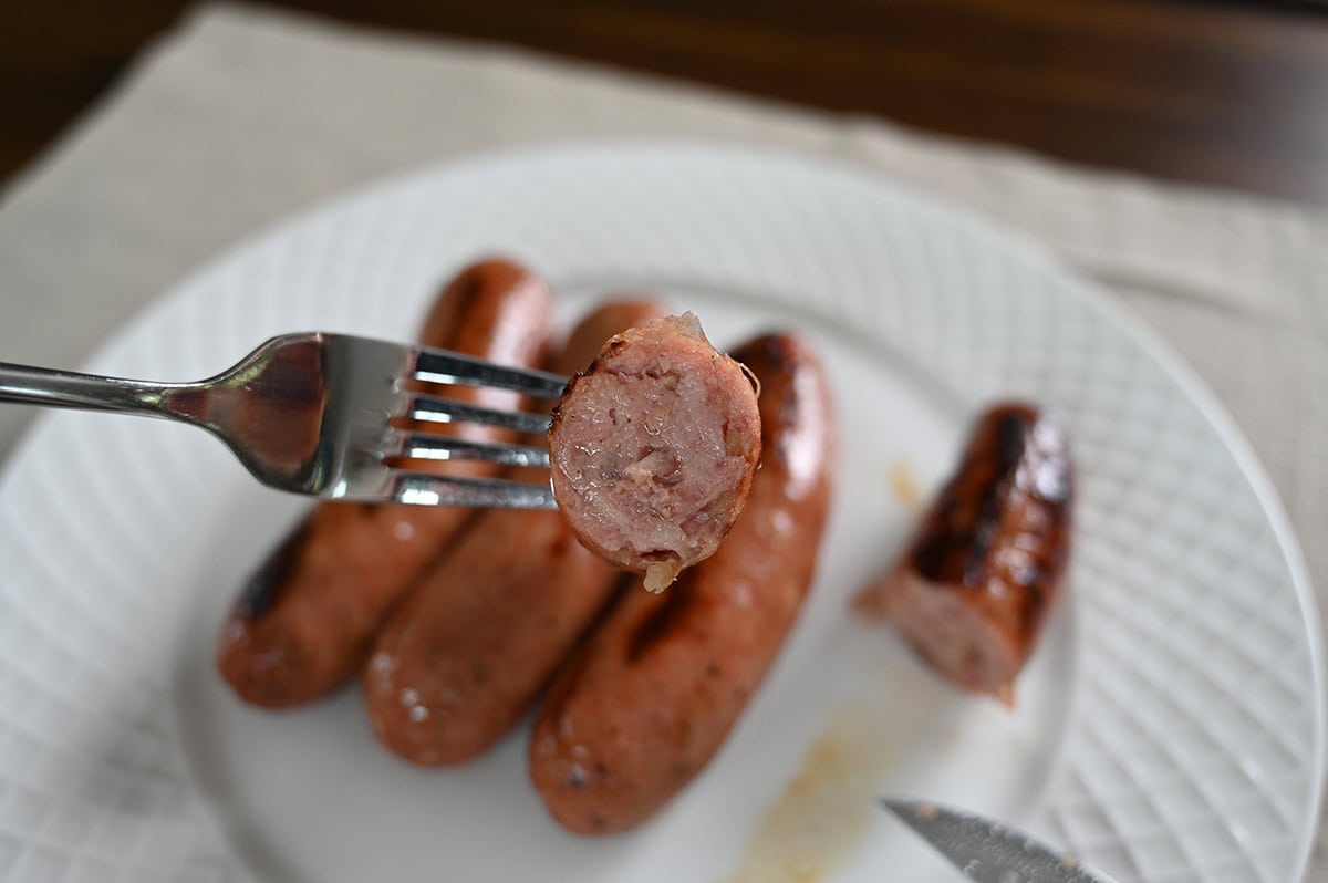 Closeup image of a fork with a slice of sausage on the fork. 