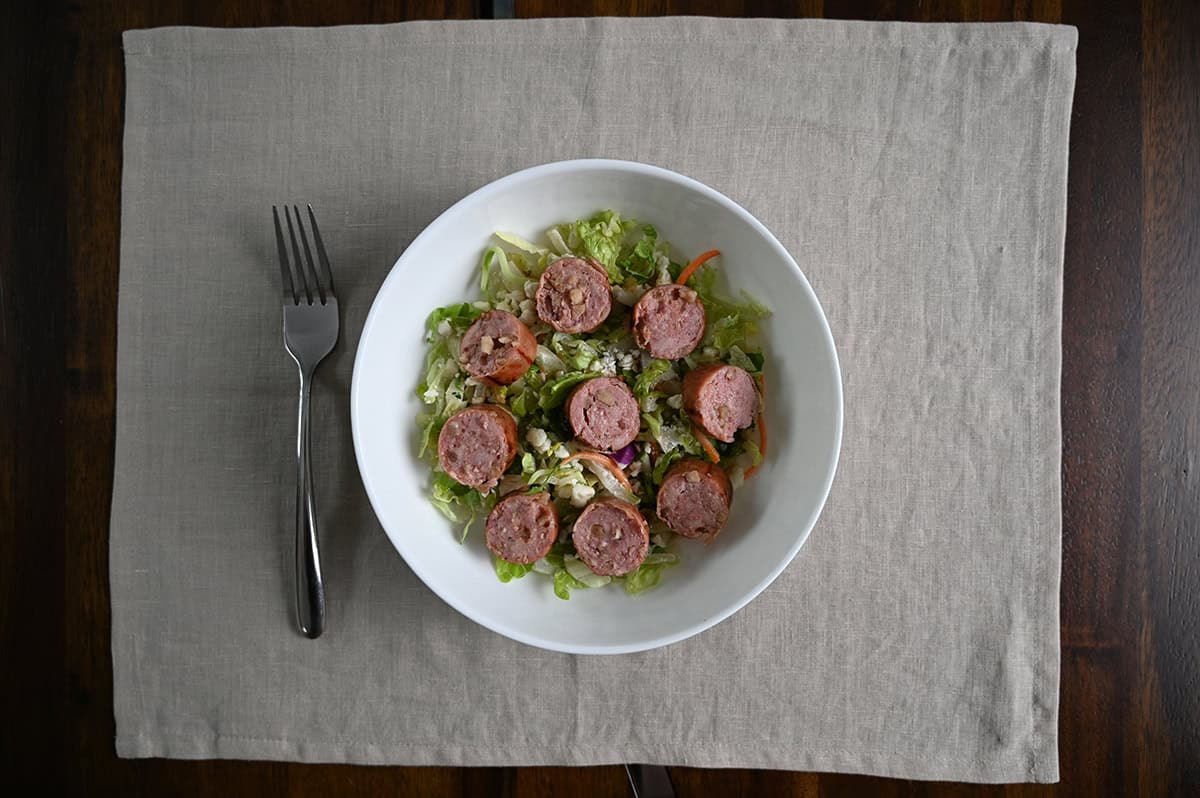 Top down image of sausage sliced and served on a bed of greens.