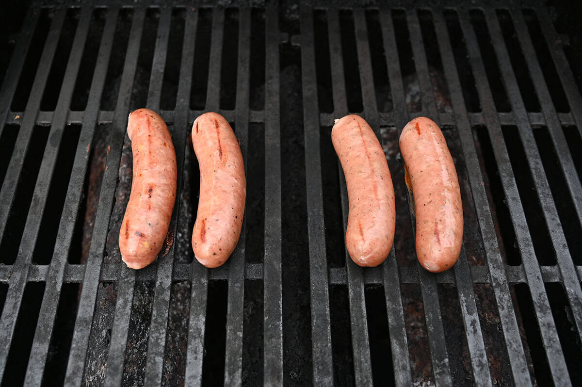 Top down image of four sausages grilling on a barbecue.