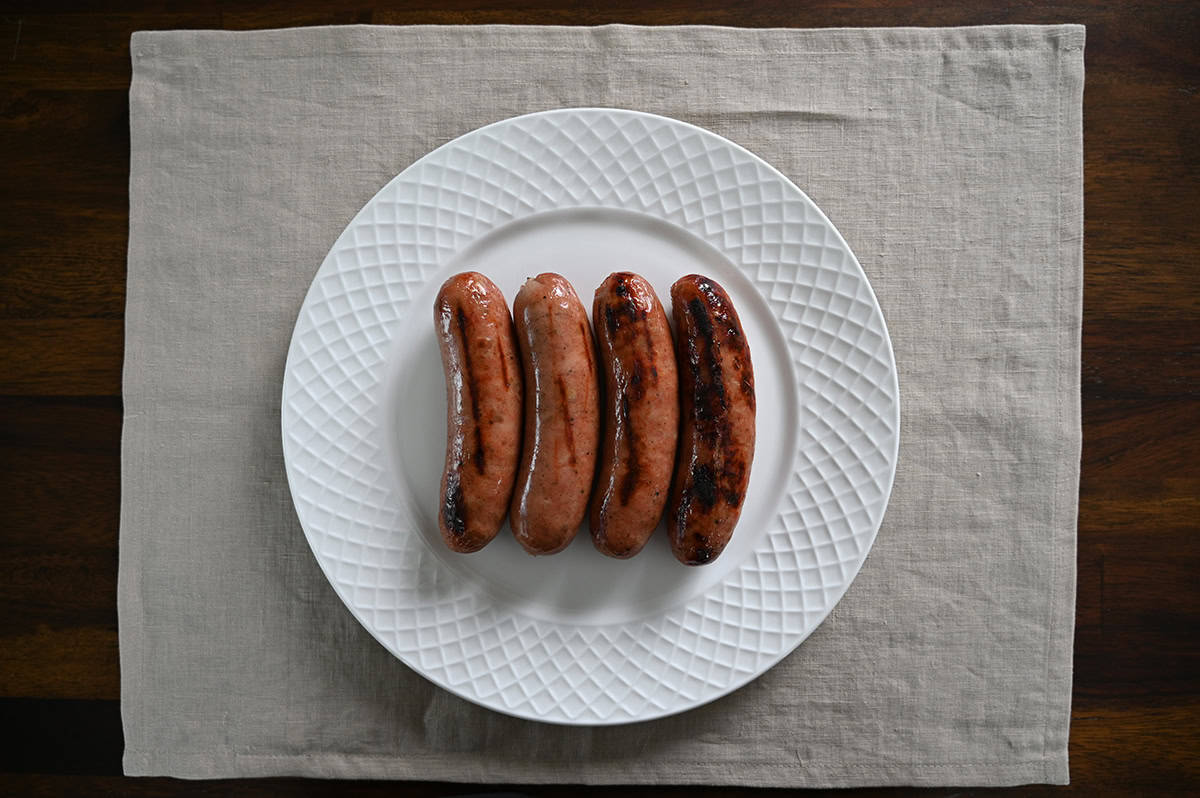 Top down image of four grilled sausages served on a white plate.