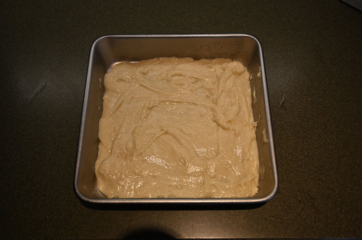 Image of the bottom layer of cake batter in a square pan before adding the topping.