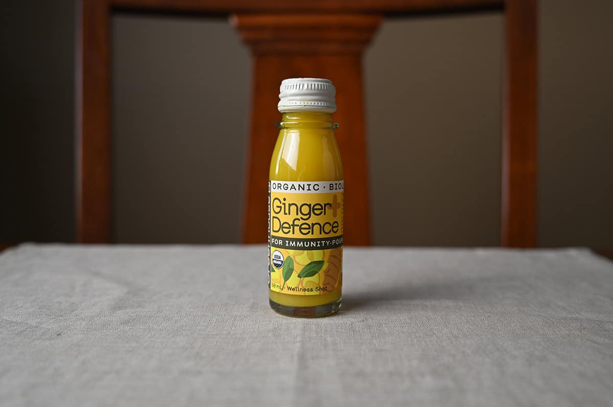 Image of one small unopened bottle of ginger defence sitting on a table.