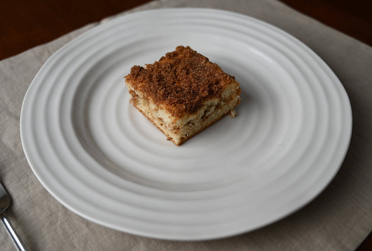 Top down side view image of a slice of cinnamon swirl cake served on a white plate.