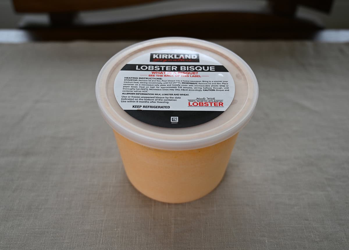 Sideview image of one container of lobster bisque sitting on a table unopened.