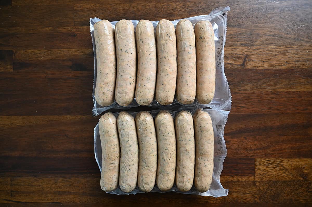 Top down image of two packs of six sausages packaged in plastic sitting on a table.