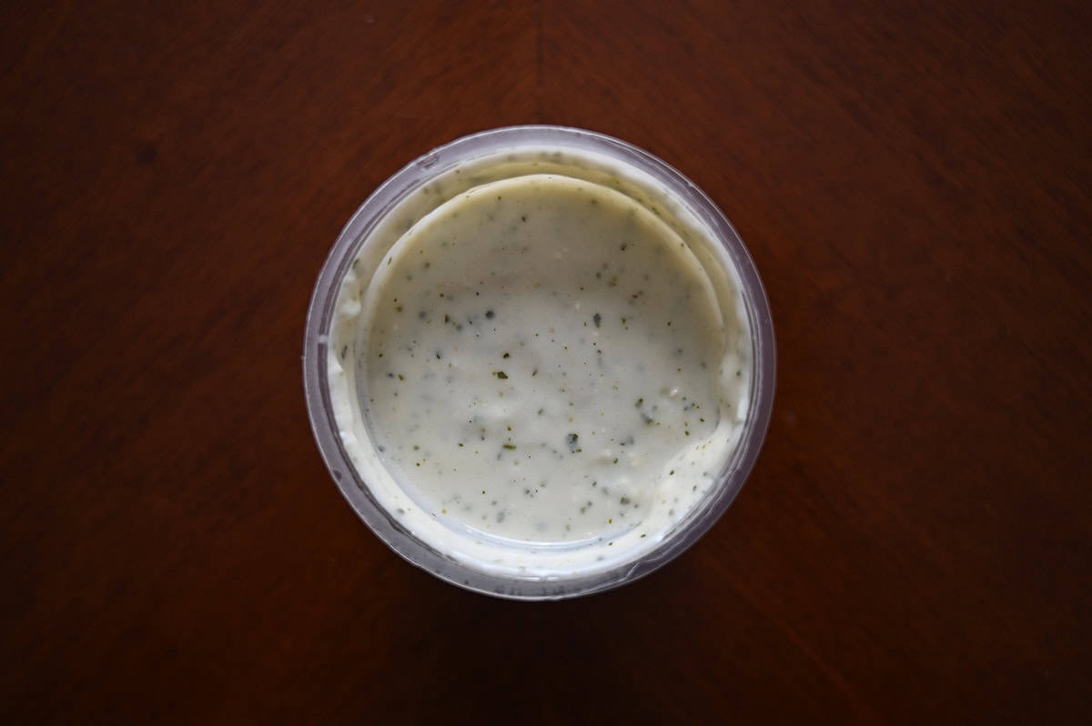Top down image of an open container of the cilantro lime cream sauce that comes with the tacos.