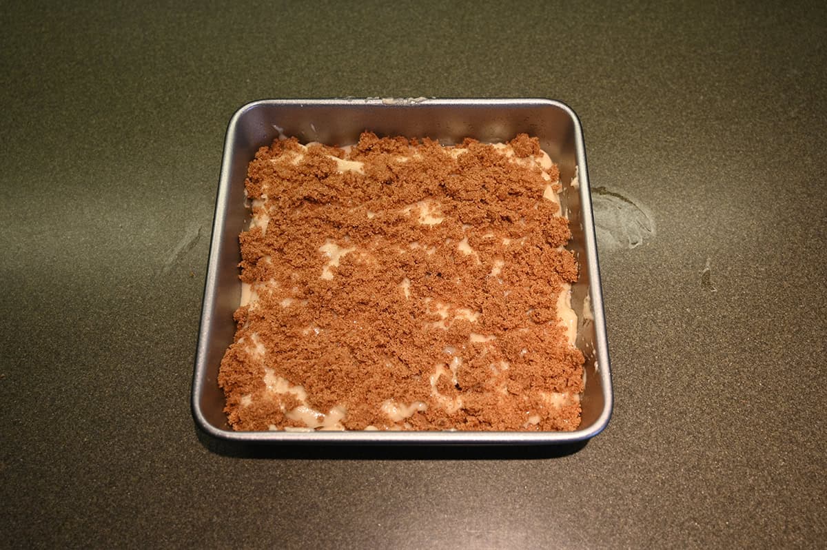 Image of the cake batter prepared in a square pan with topping on it before going in the oven.