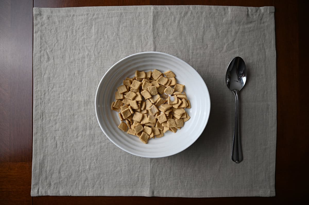 Top down image of a bowl of Catalina Crunch cereal with milk, there is a spoon beside the bowl. 