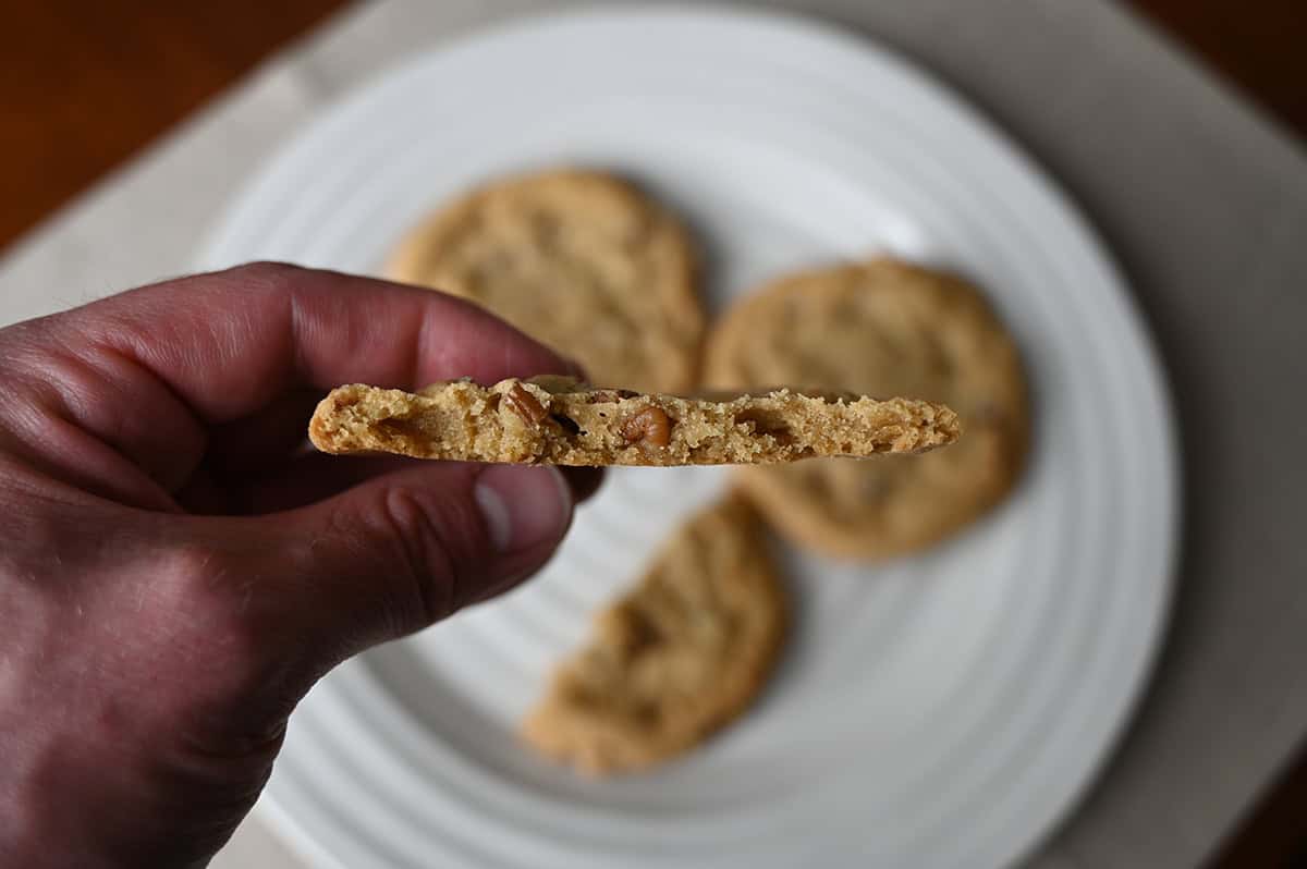 Sideview image of a hand holding one cookie close to the camera with a few bites taken out of it so you can see the center of the cookie.