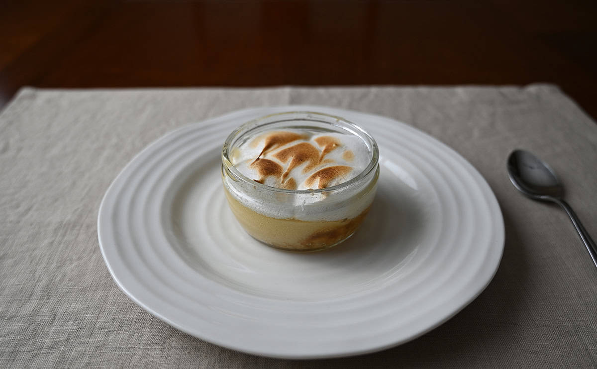Image of one heated lemon meringue pie sitting on a white plate. 