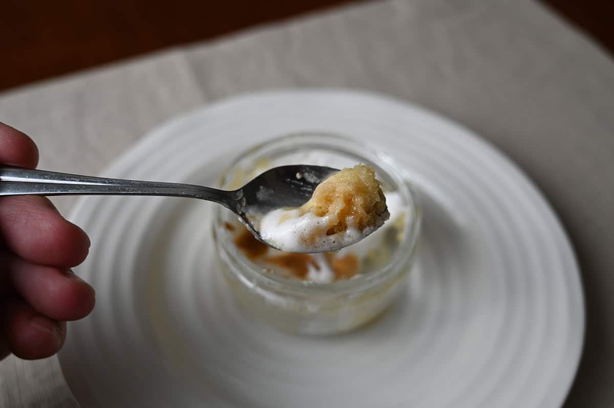 Image of a spoon with lemon meringue pie on it close to the camera hovering over the dish.