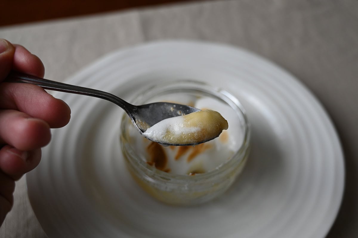 Closeup image of a spoon with lemon meringue pie on it hovering over the ramekin of lemon meringue pie.