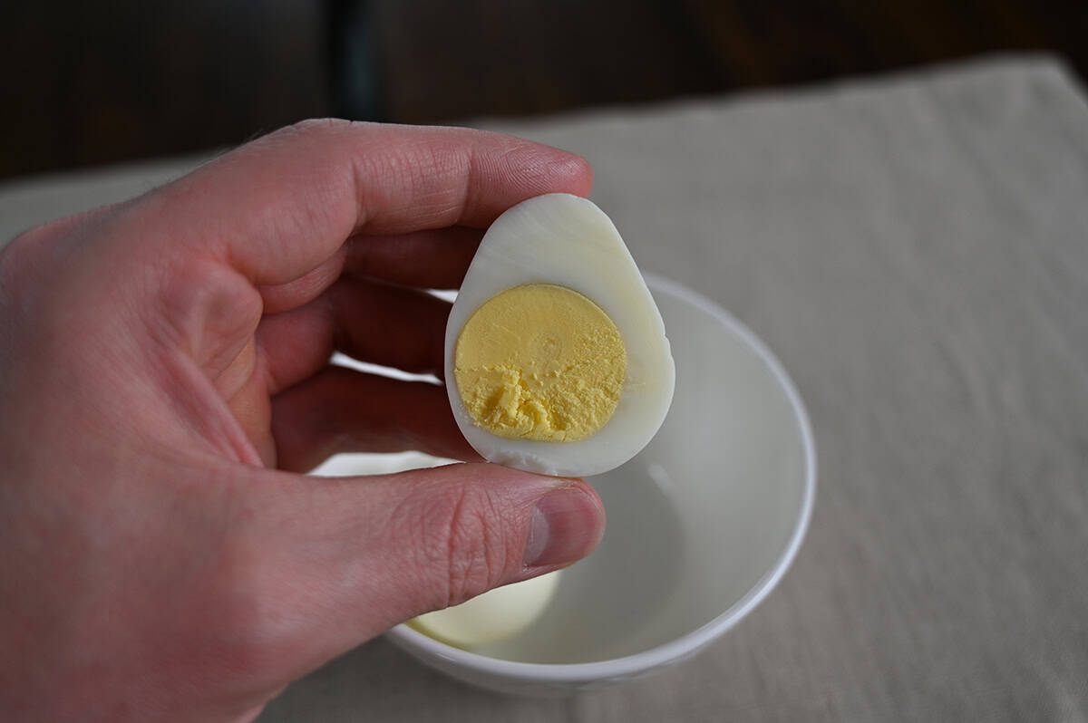 Closeup image o a hand holding one hard boiled egg cut in half so you can see the center.