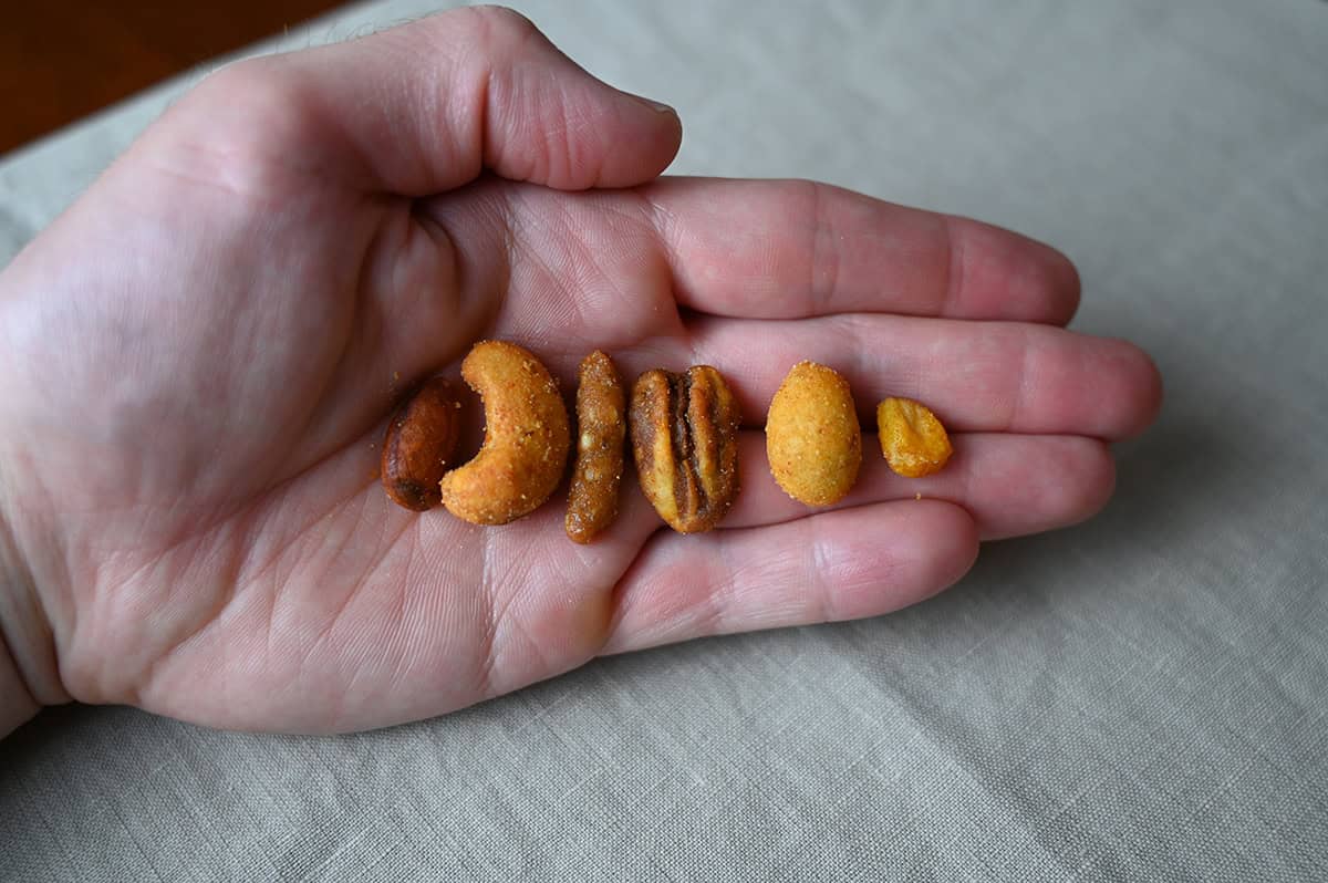 Closeup image of a palm of a hand with the hand holding one of each component of the snack mix. 