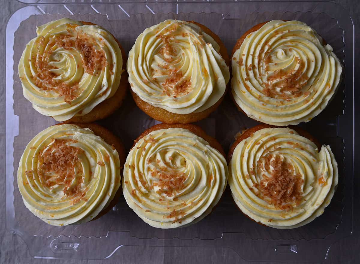 Top down image of an open container of pineapple coconut mini cakes showing what the cake tops look like.