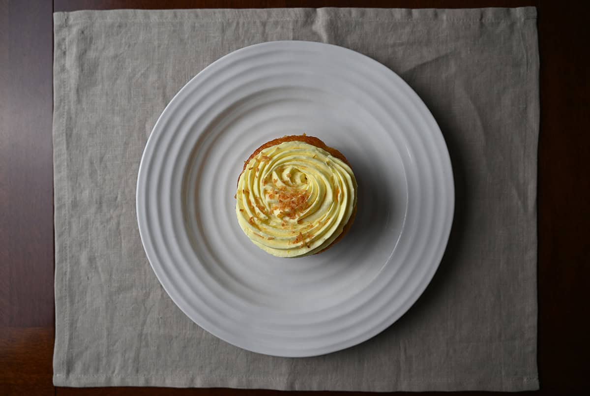 Top down image of one pineapple coconut mini cake served on a white plate so you can see the icing and streusel on the cake.