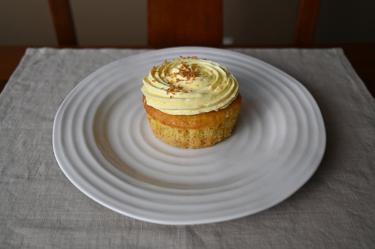 Side view image of one mini pineapple coconut mini cake taken out of the wrapper and served on a white plate. 