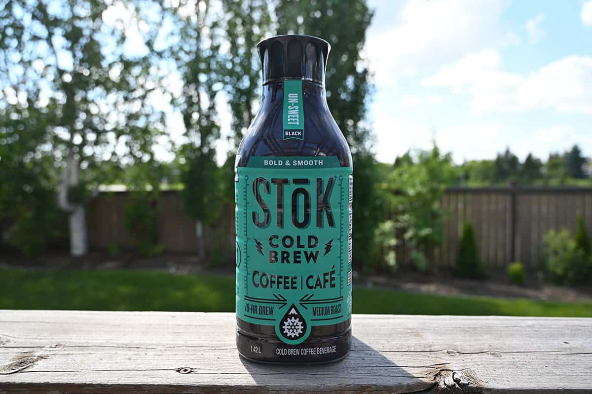 Image of the Costco Stok Cold Brew Coffee sitting on a deck outside unopened with trees in the background.