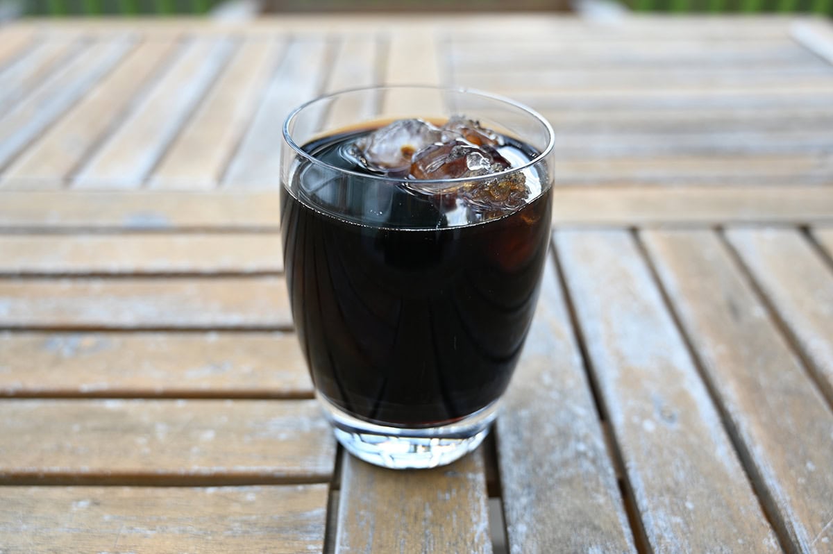 Image of one glass of cold brew coffee with ice in it, sitting on a table.