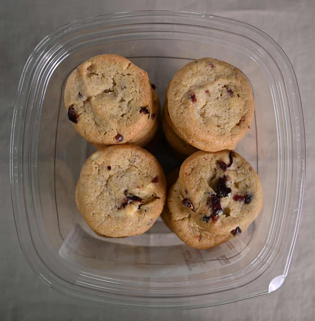 Top down image of an opened container of white chocolate cranberry cookies sitting on a table.