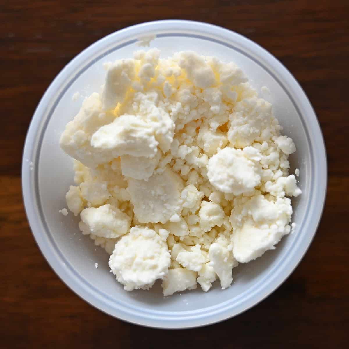 Top down image of an open container of feta cheese. 