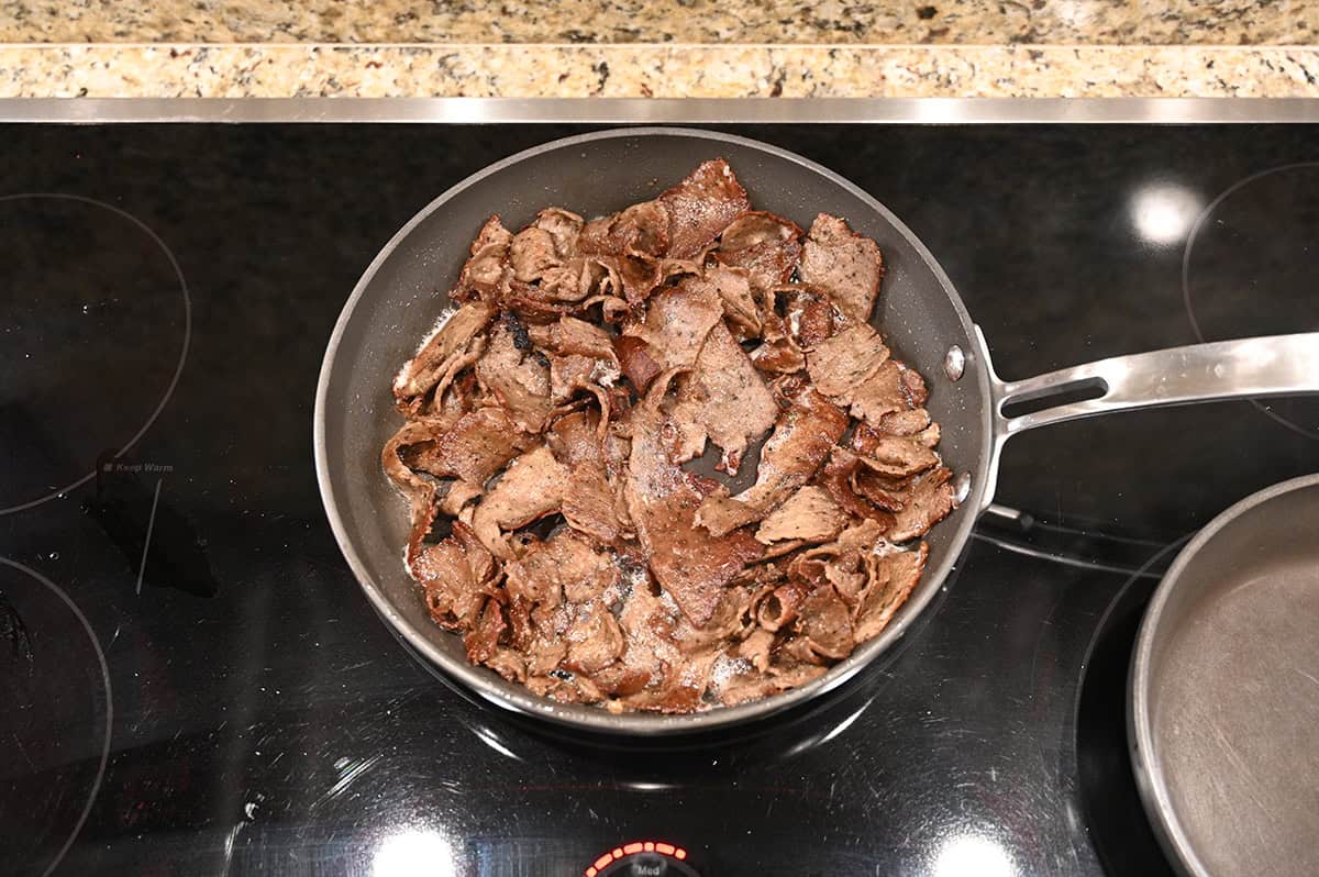 Top down image of donair meat being heated in a frying pan on the stovetop.