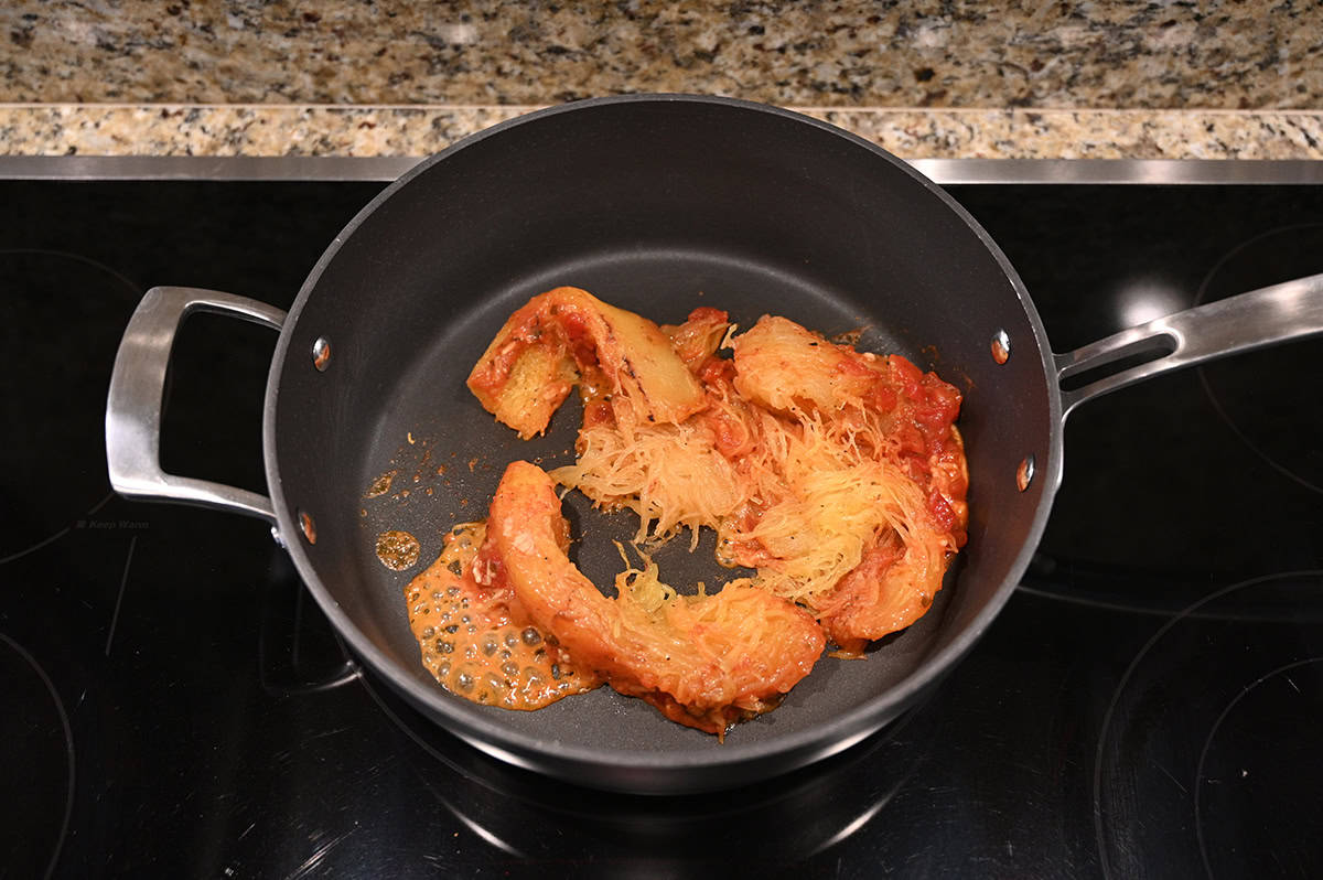 Top down image of spaghetti squash being cooked in a frying pan on the stovetop.