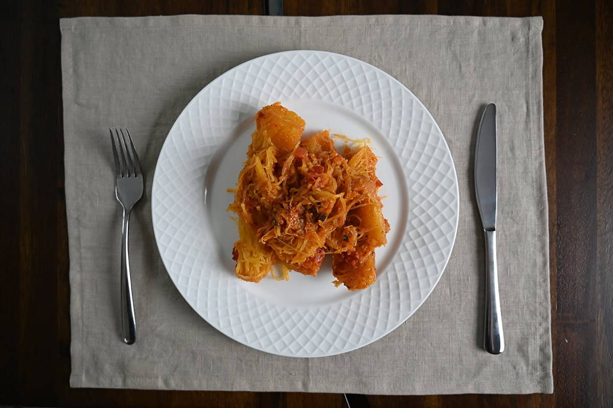 Top down image of cooked spaghetti squash served on a white plate.