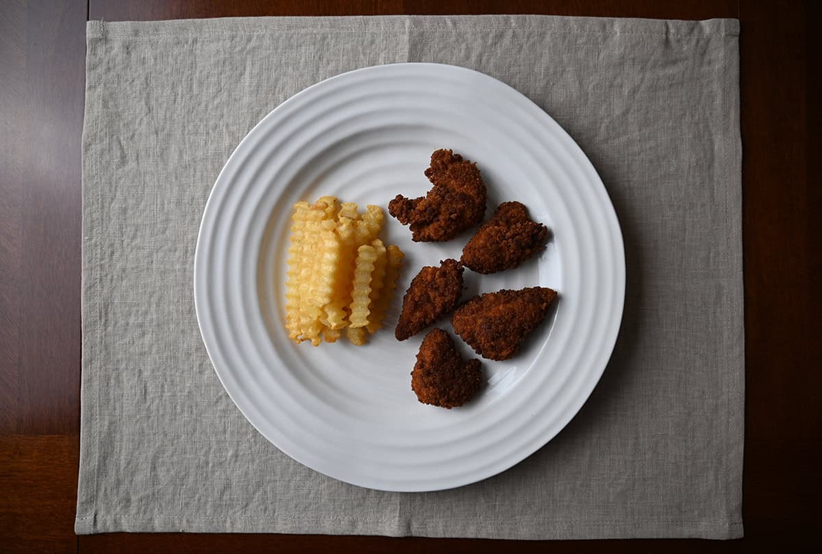 Top down image of a plate of chicken tenders with fries. 