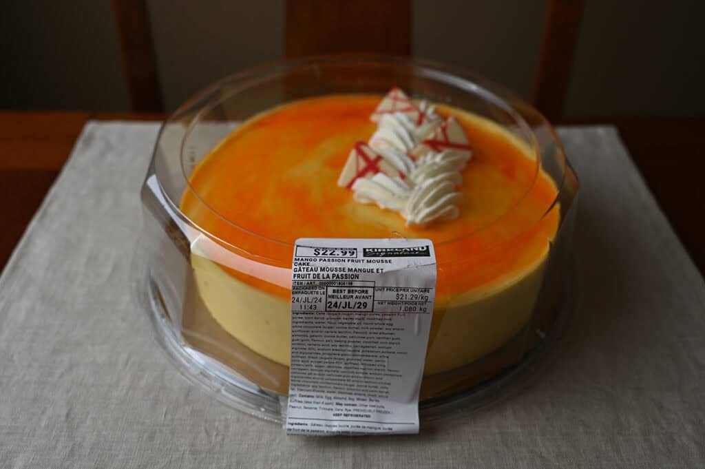 Image of the Costco Kirkland Signature Mango Passion Fruit Mousse Cake sitting on a table packaged and unopened.