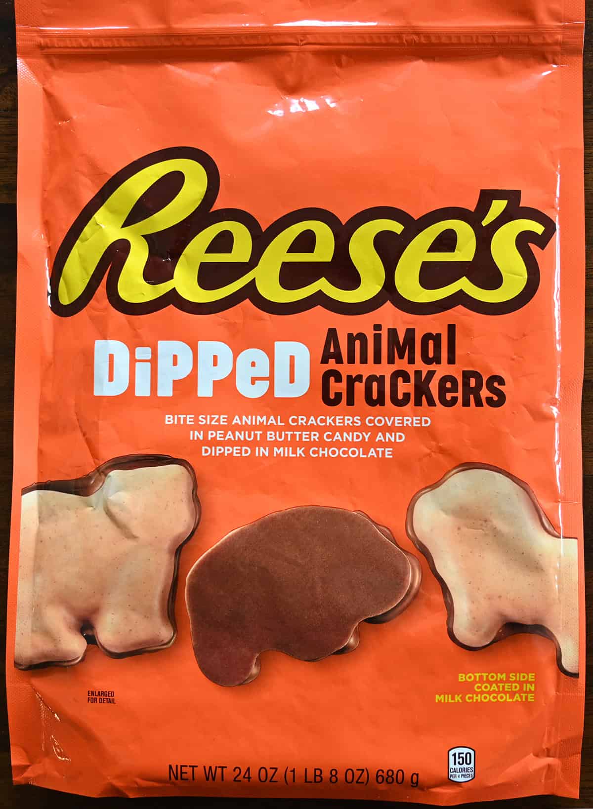 Closeup image of the front of the bag of animal crackers showing the bottom side of the cracker is coated in milk chocolate and the top side is coated in peanut butter candy.