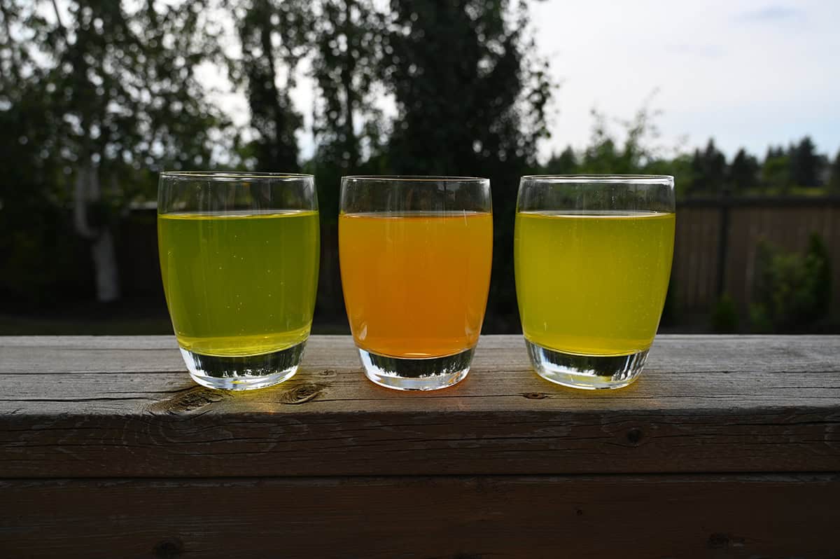 Image of three clear glasses with Celsius poured into them. From left to right, peach vibe, sparkling orange and tropical vibe.