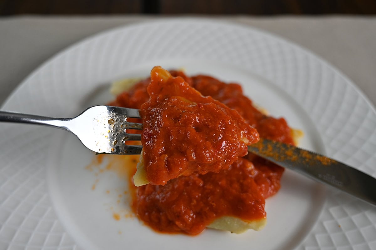 Closeup image of a fork with pasta on it covered in tomato sauce.