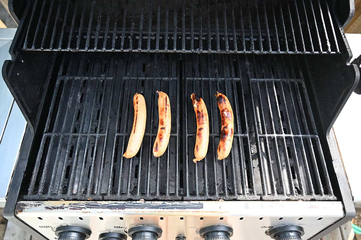 Image of four sausages being grilled on a barbecue.