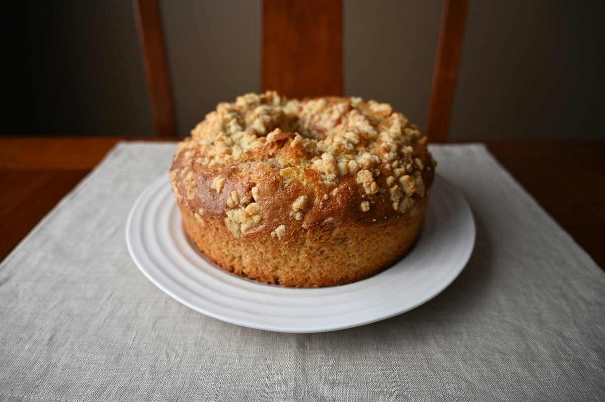 Sideview image of one whole coffee cake unpackaged and sitting on a white plate.