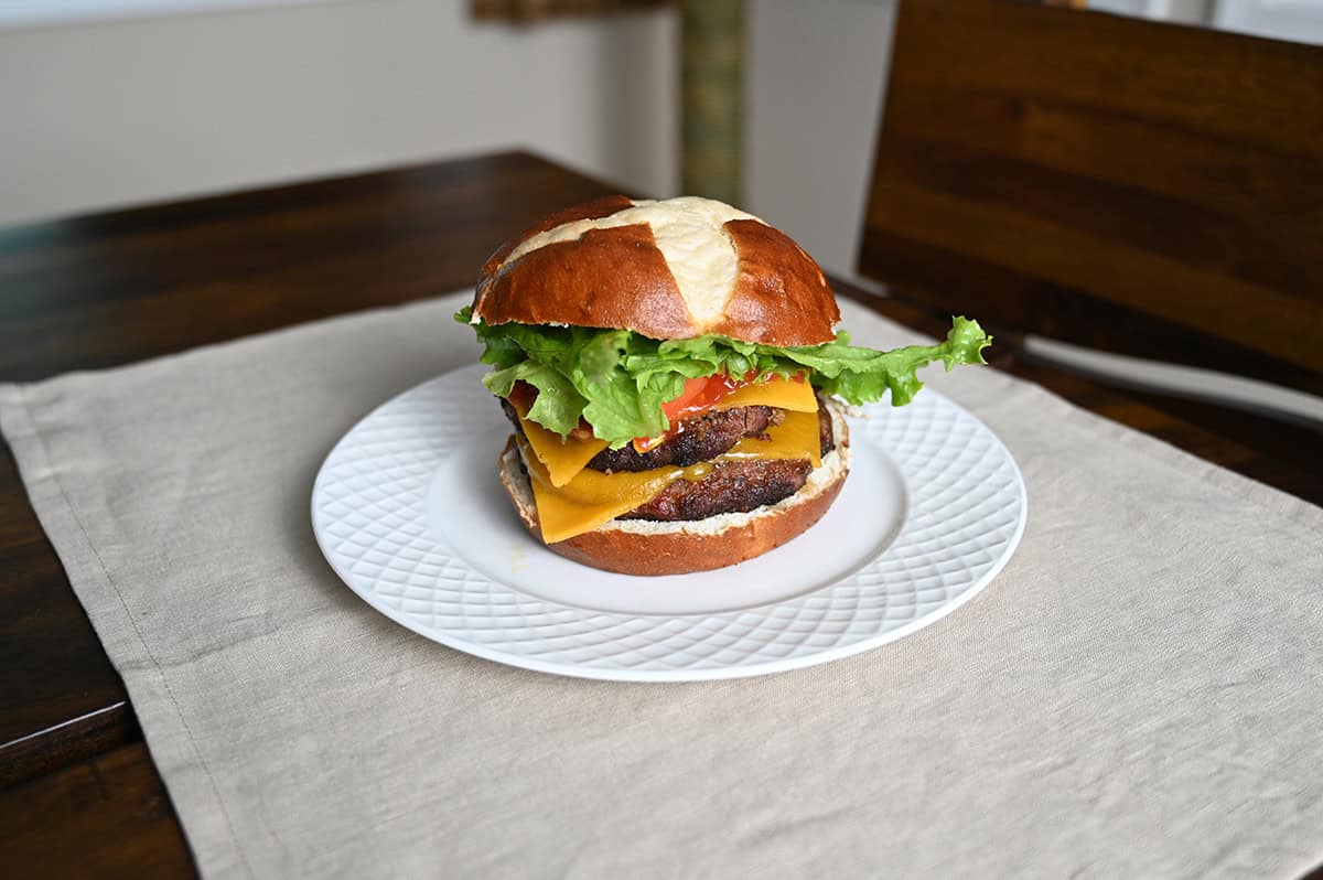 Closeup side view image of a large double cheeseburger served on a white plate.