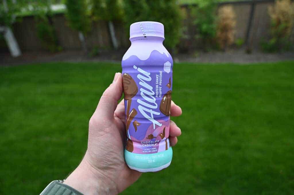 Image of a hand holding on protein shake bottle close to the camera.