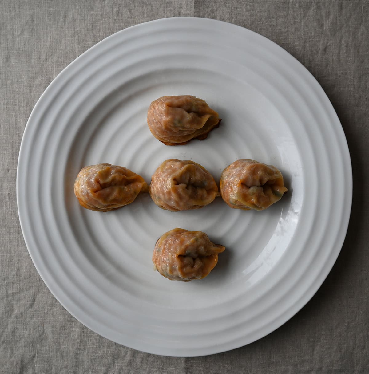 Top down image of five cooked dumplings sitting on a plate.