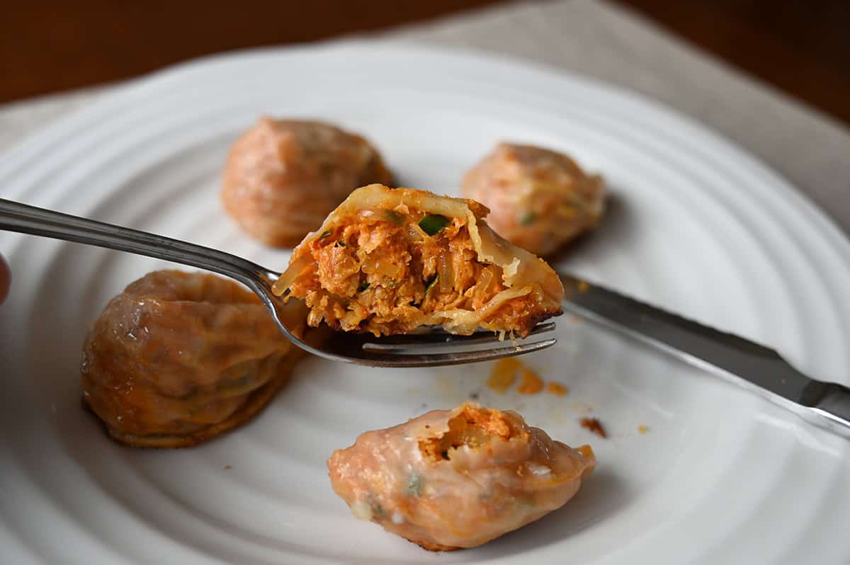 Closeup image of a fork with a dumping on it cut in half so you can see the filling in the dumpling. 